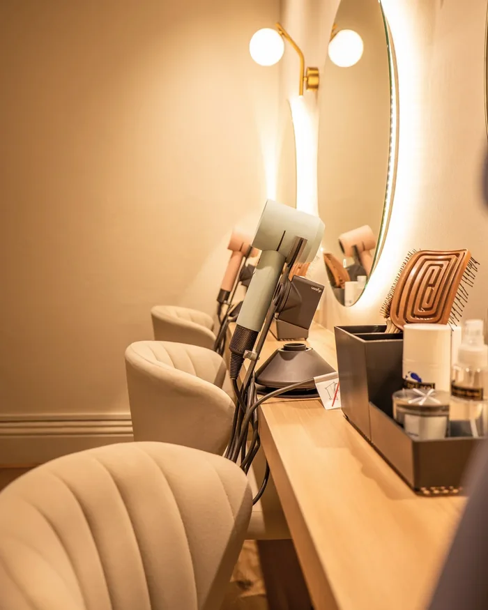 A drying station at Hikari with a round mirror, wall lights and a hairdryer