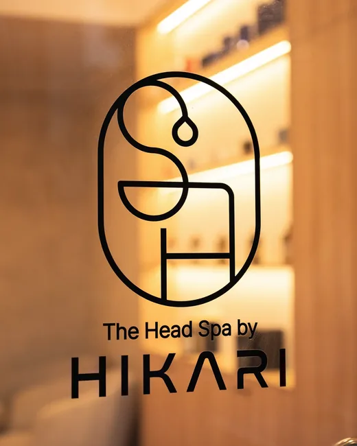 The Hikari logo on the glass at the entrance, with the lit reception shelves behind